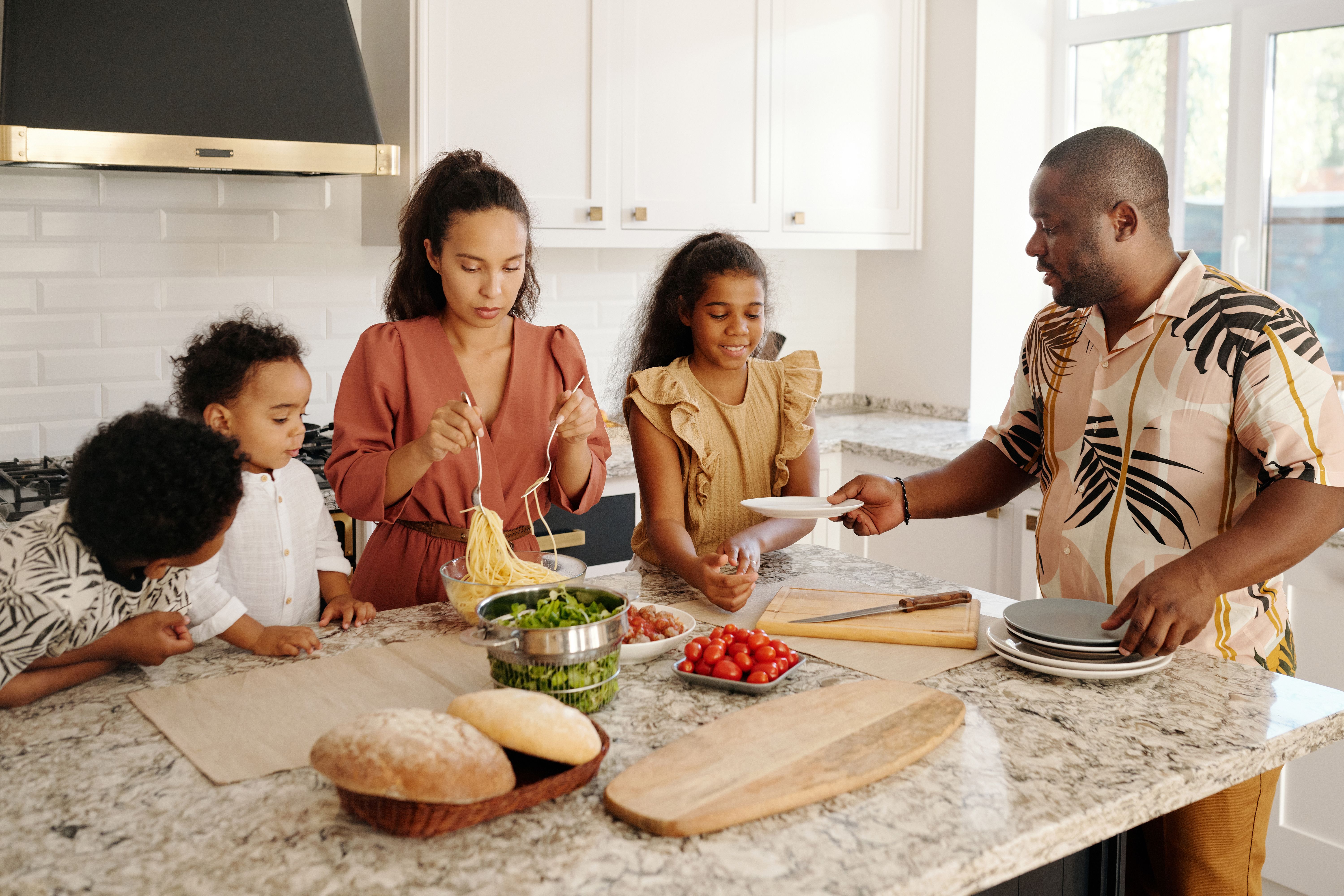 A family with three children preparing a meal together in a bright kitchen